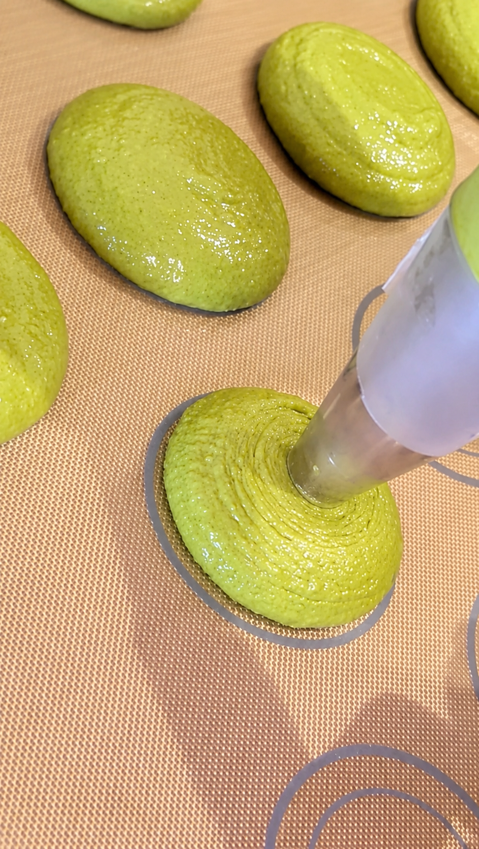 Pochage de la pâte à macaron pistache sur tapis en silicone