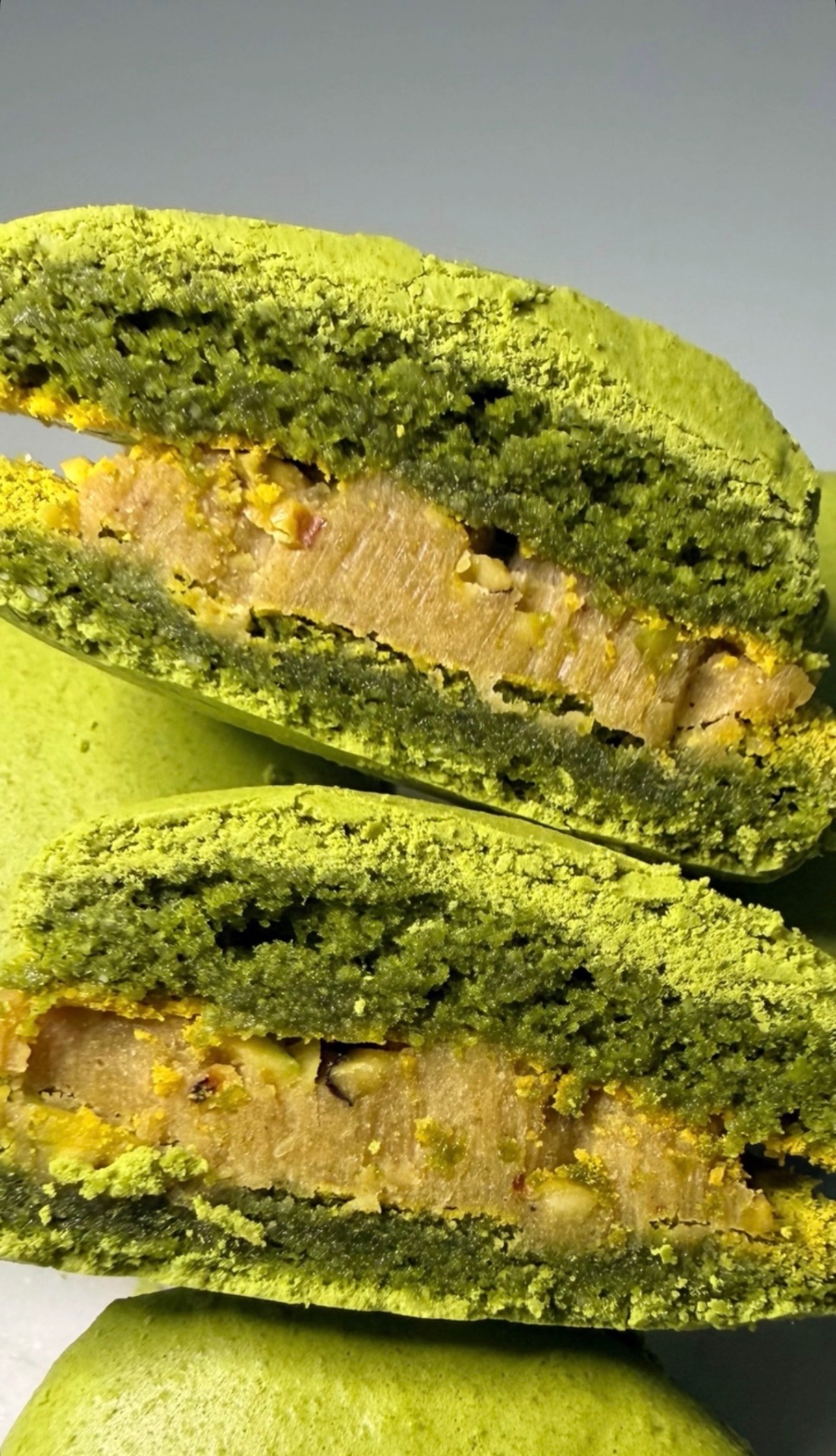 Gros plan sur un macaron pistache coupé, garniture aux éclats de pistache